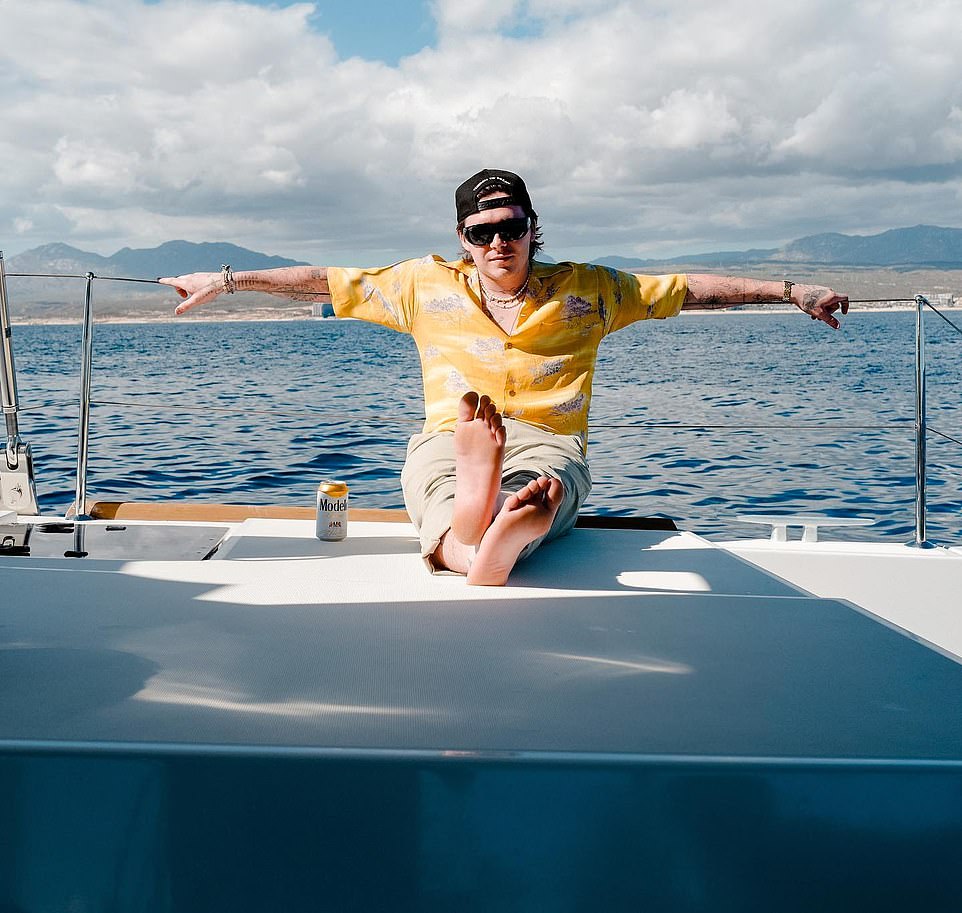 Relaxing: The British-born star lounged on the boat that floated on the wavy blue water as he sipped on a can of Modelo
