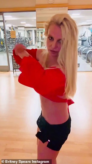 Spears donned an orange long-sleeved top with black shorts as she performed in a gym setting