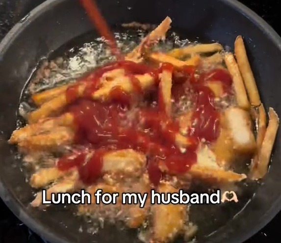 Ketchup being poured over fries cooking in a pan; lunch for husband.