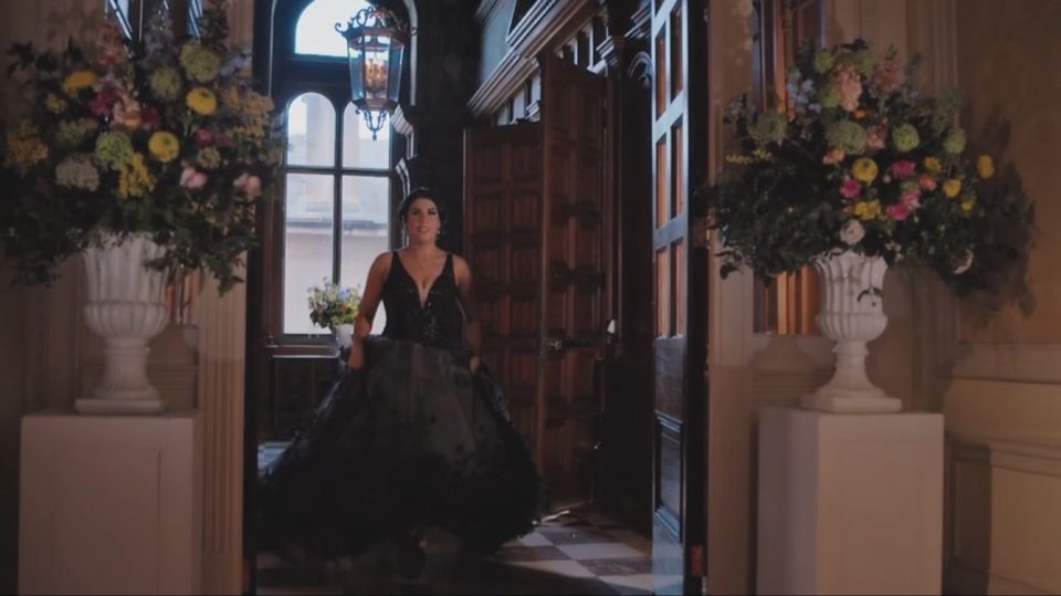 Maeve from Married at First Sight wearing a black gown and walking through a doorway.