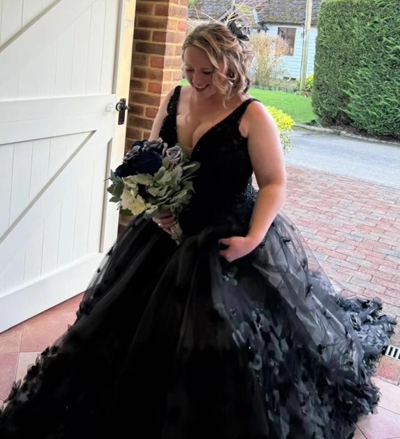 A woman in a black wedding dress and holding a bouquet, with text overlay "when #mafsuk steals your wedding dress".