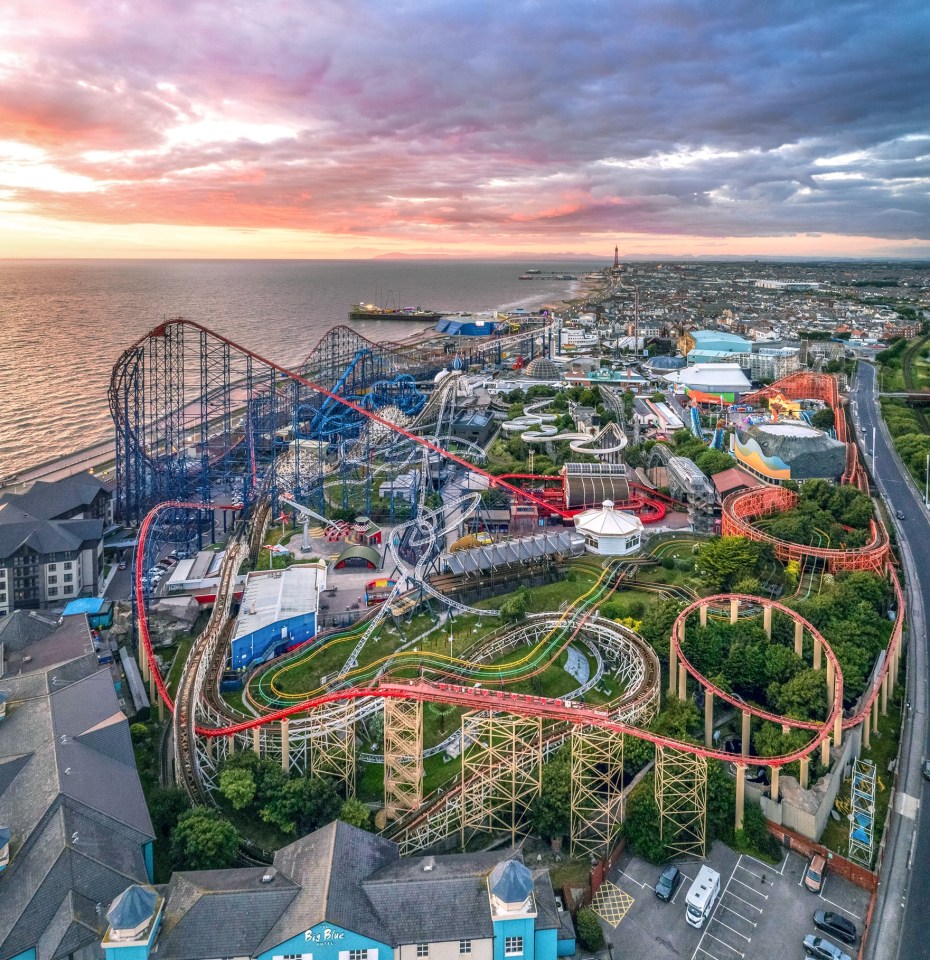 Aerial view of Blackpool Pleasure Beach amusement park with multiple roller coasters and rides, overlooking the sea at sunset.
