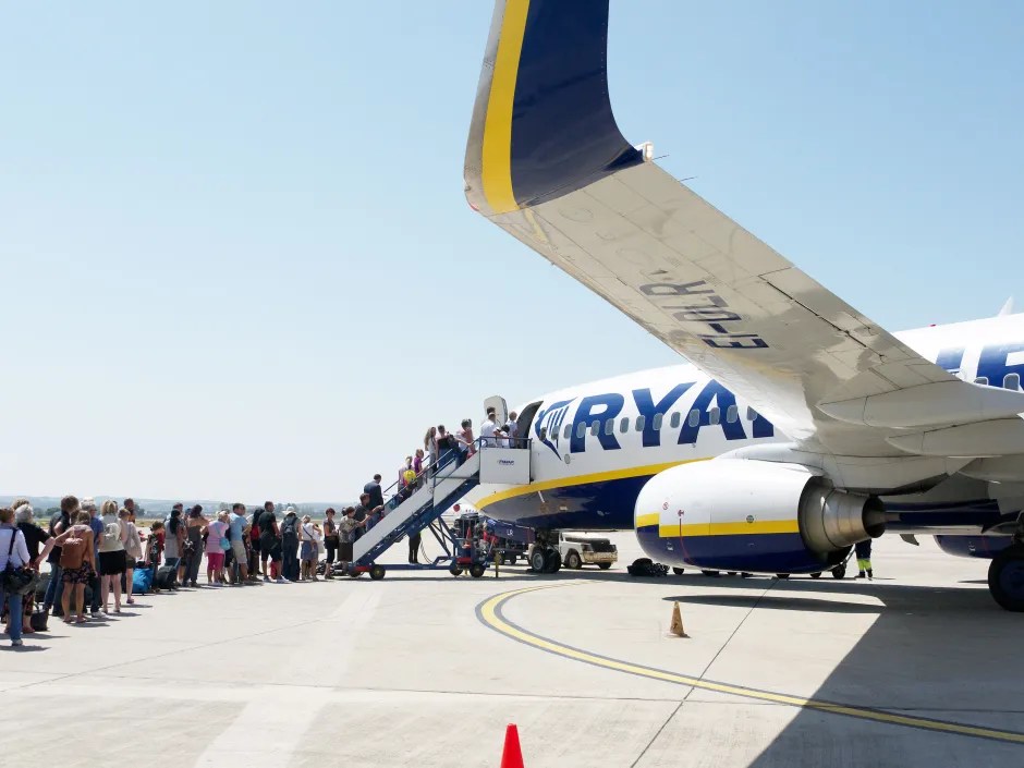 Ryanair passengers queue on the airfield to board an airplane.