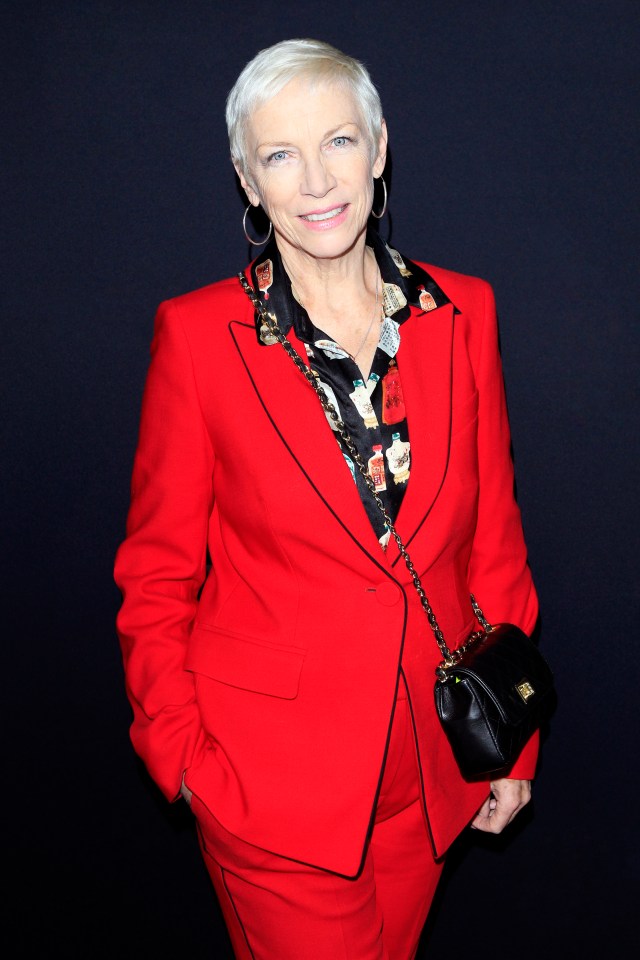 Annie Lennox in a red suit and patterned shirt.