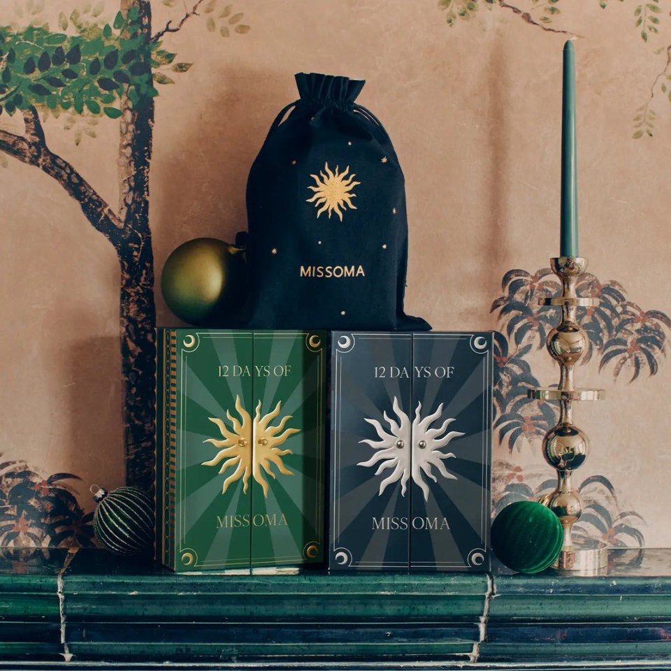 Two Missoma Advent Calendars, a green "12 Days of Missoma" box and a dark blue "12 Days of Missoma" box, with a Missoma dust bag and Christmas decorations.