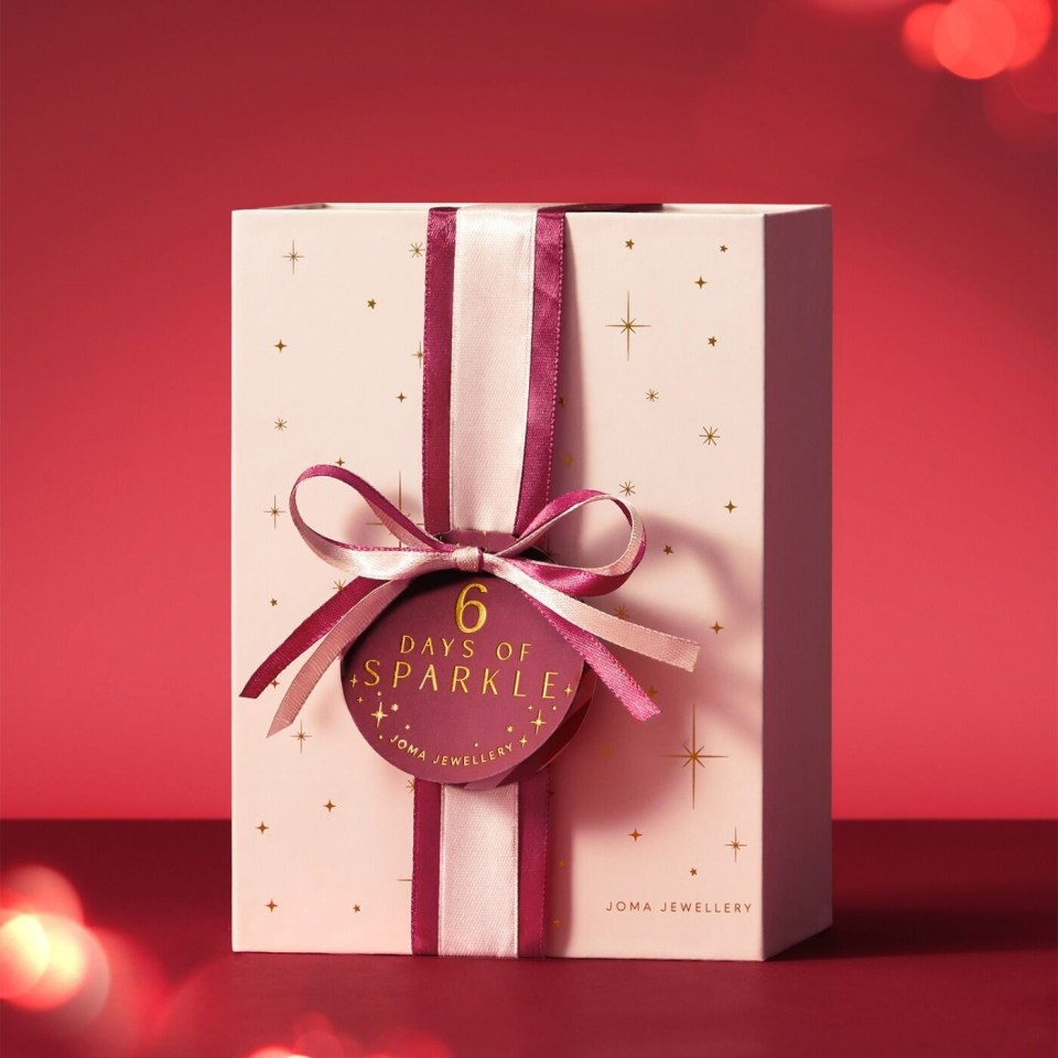 Joma Jewellery 6 Days of Sparkle advent calendar, a pink box tied with a maroon and pink ribbon, on a red background.