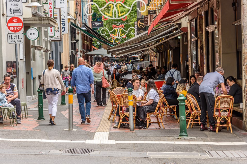People walking and dining outdoors at cafes and restaurants in Hardware Lane, Melbourne, Australia.