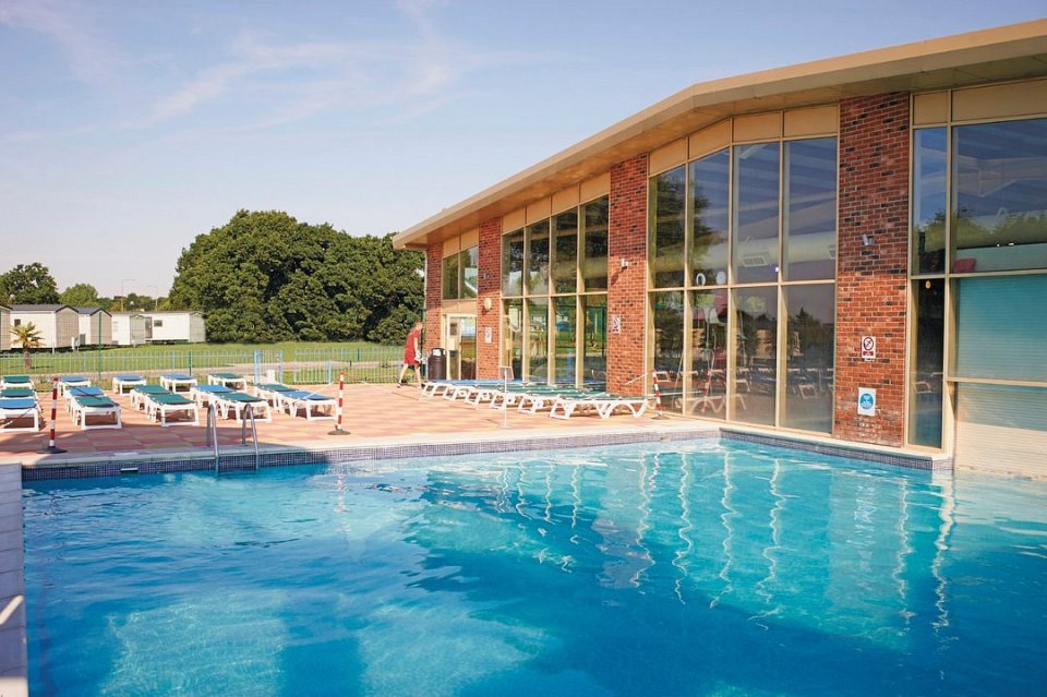 Highfield Grange Holiday pool area with building and lounge chairs.