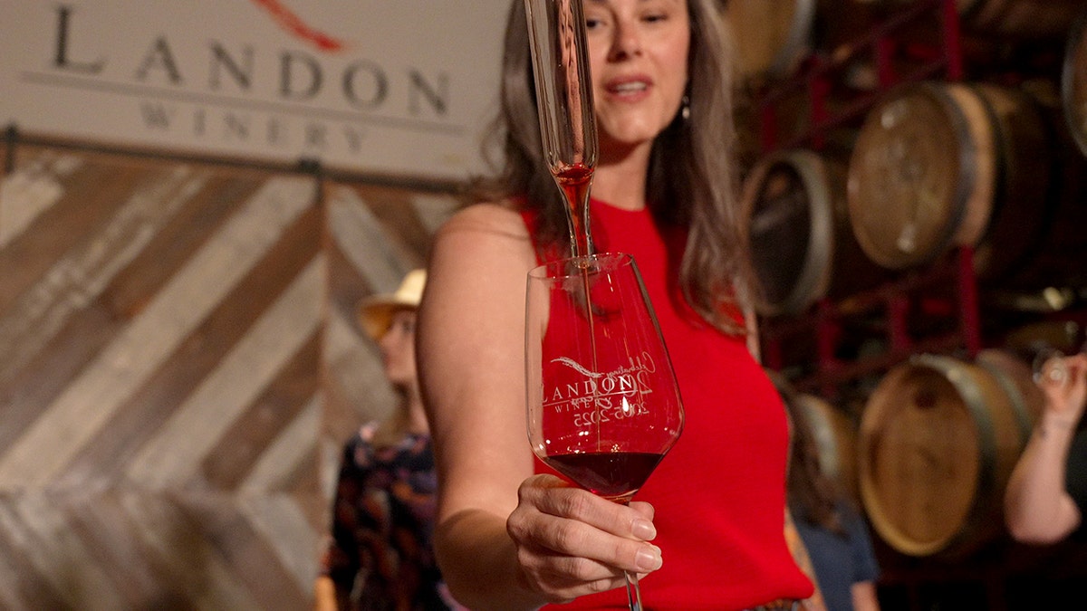 A woman samples red wine at a winery.