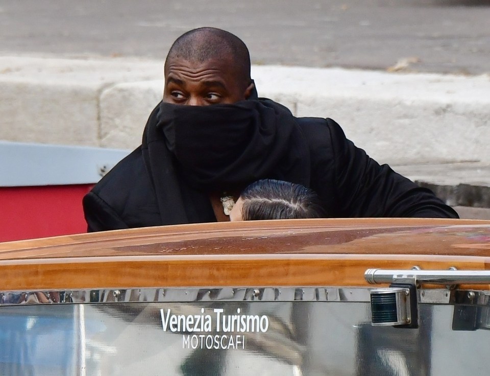 Kanye West on a river taxi with his face covered and Bianca Censori beside him.