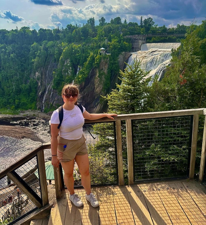 A woman standing on a wooden deck overlooking a waterfall.