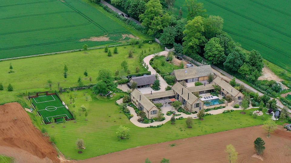 Aerial view of the Beckham family home in Great Tew, featuring a large estate, an outdoor swimming pool, and a private soccer field.