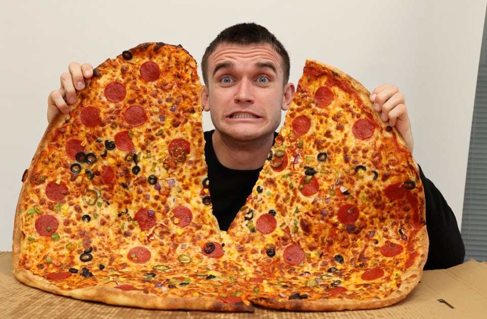 A man struggles to hold a very large pepperoni pizza.