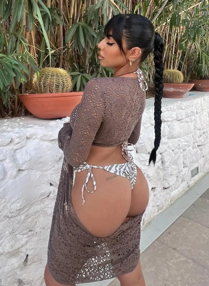 a woman in a bikini is standing in front of a wall with potted plants