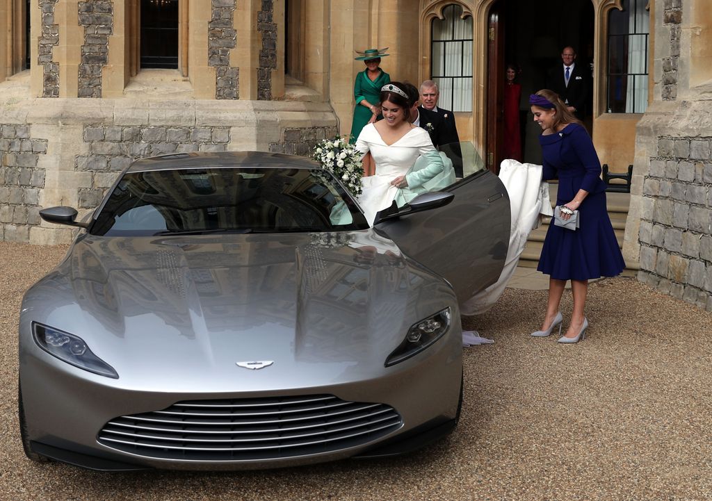 Princess Eugenie in bridal gown getting into car helped by princess beatrice