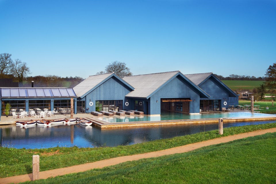 Soho Farmhouse spa and hotel with an outdoor pool and small boats on a lake.