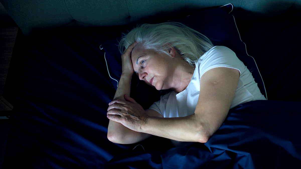 senior woman lies awake in bed at night