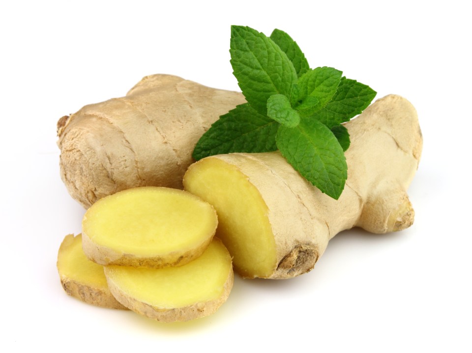Ginger root, partially sliced, with a sprig of fresh peppermint leaves.