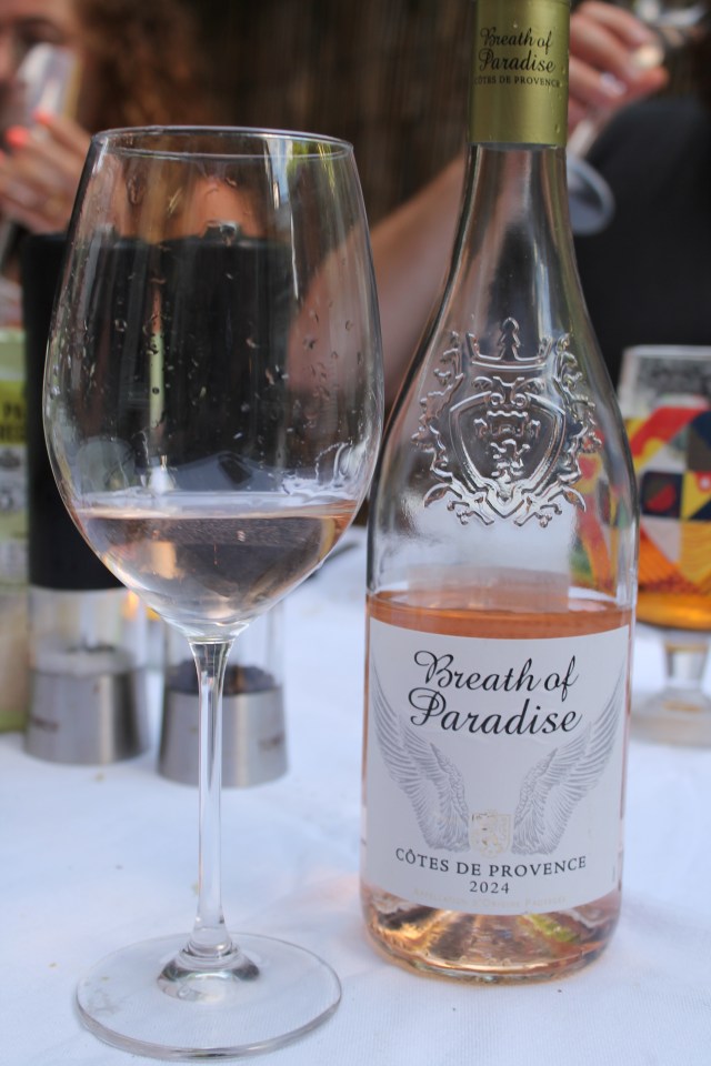 A glass of rosé wine next to a bottle of Breath of Paradise rosé.