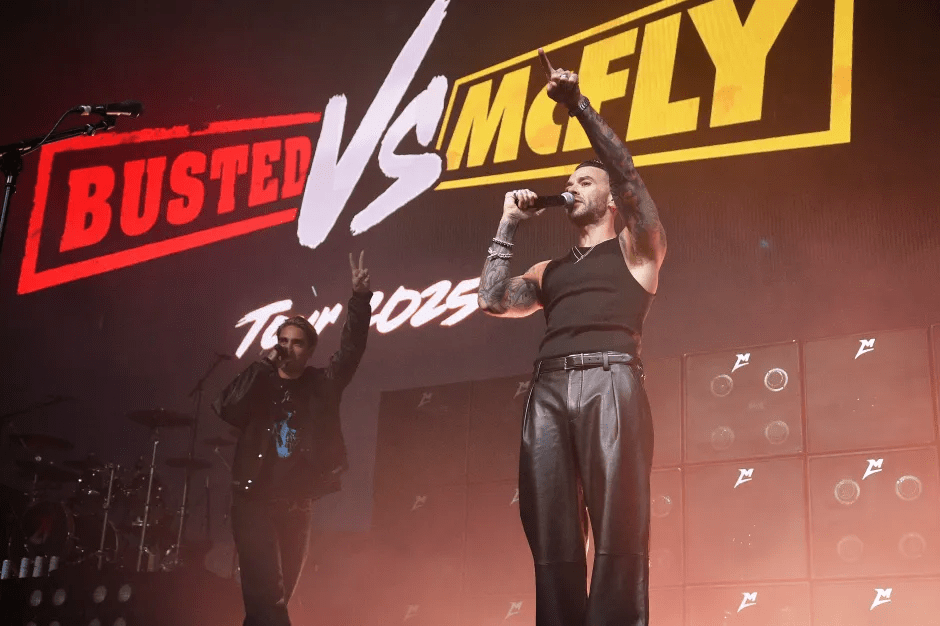 Two men performing on stage in front of a "Busted vs McFly Tour 2025" screen.