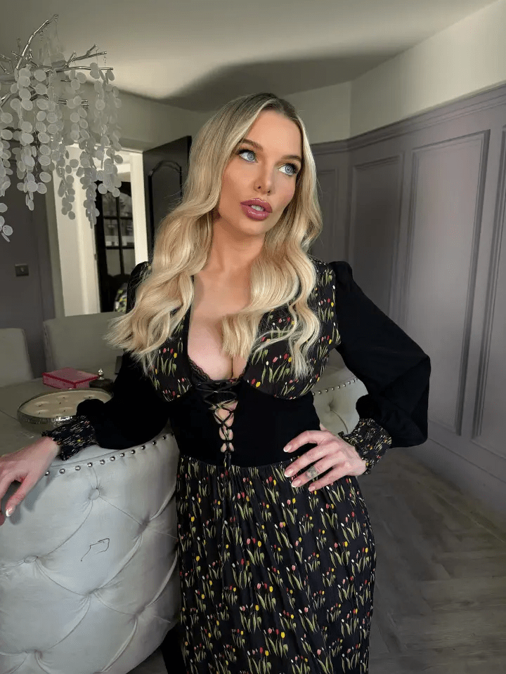 Woman with long blonde hair wearing a black floral dress with a lace-up bodice.