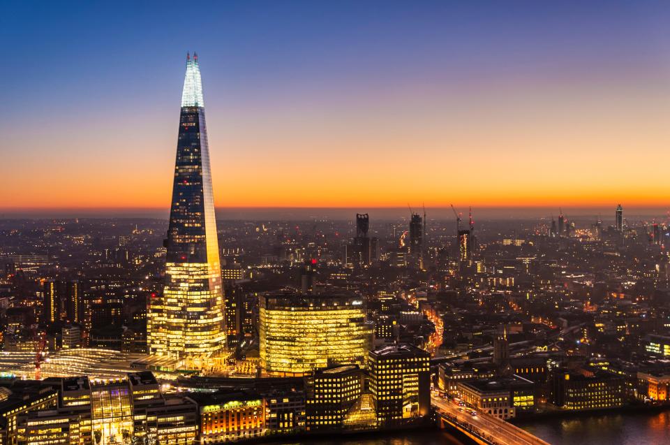 London cityscape at night with The Shard skyscraper illuminated, against a sunset sky.