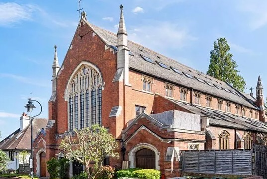 Katherine Ryan's gothic home, formerly a church, with a large arched window and a long sloped roof with skylights.