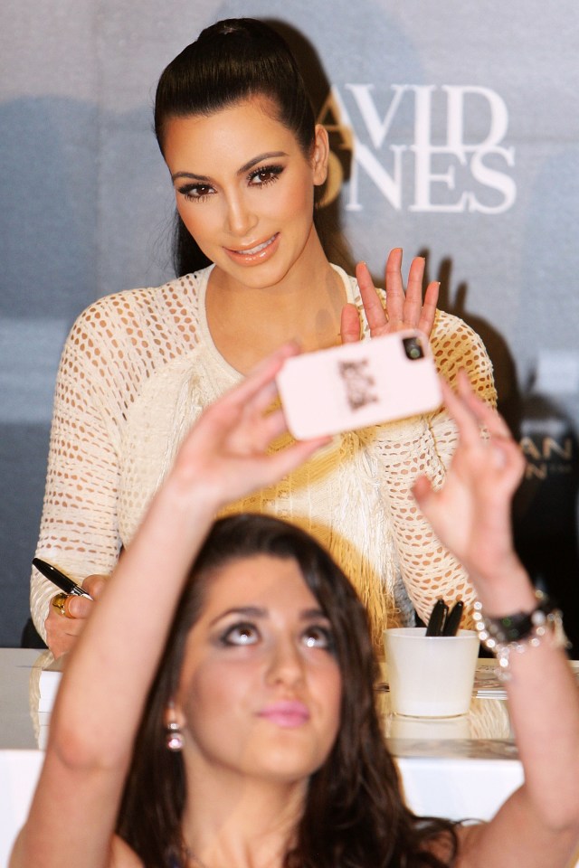Kim Kardashian waves to fans at a promotion event for her Kardashian Kollection Handbag line.