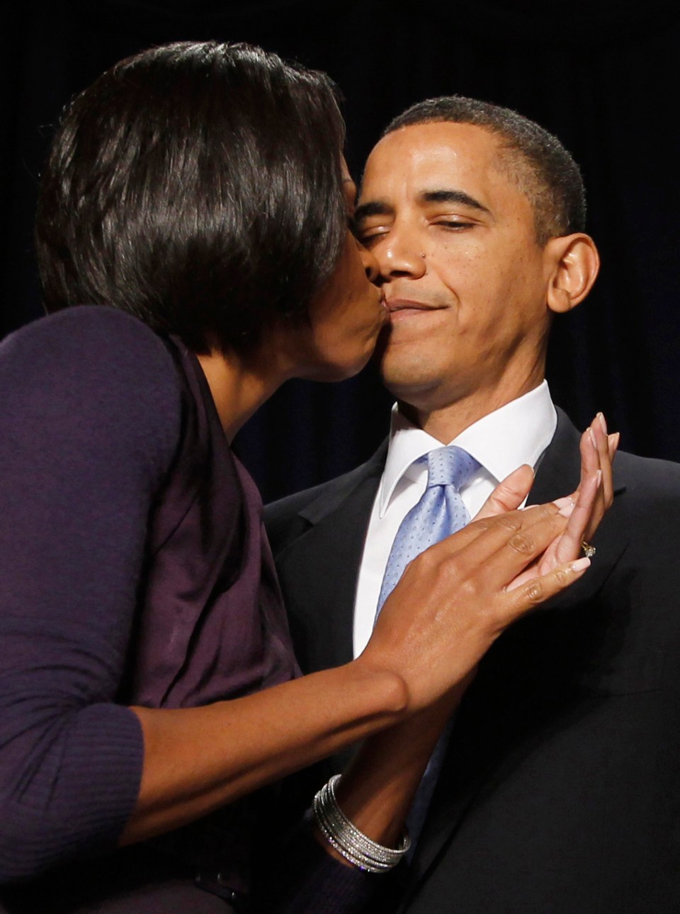 Michelle Obama kisses Barack Obama on the cheek.
