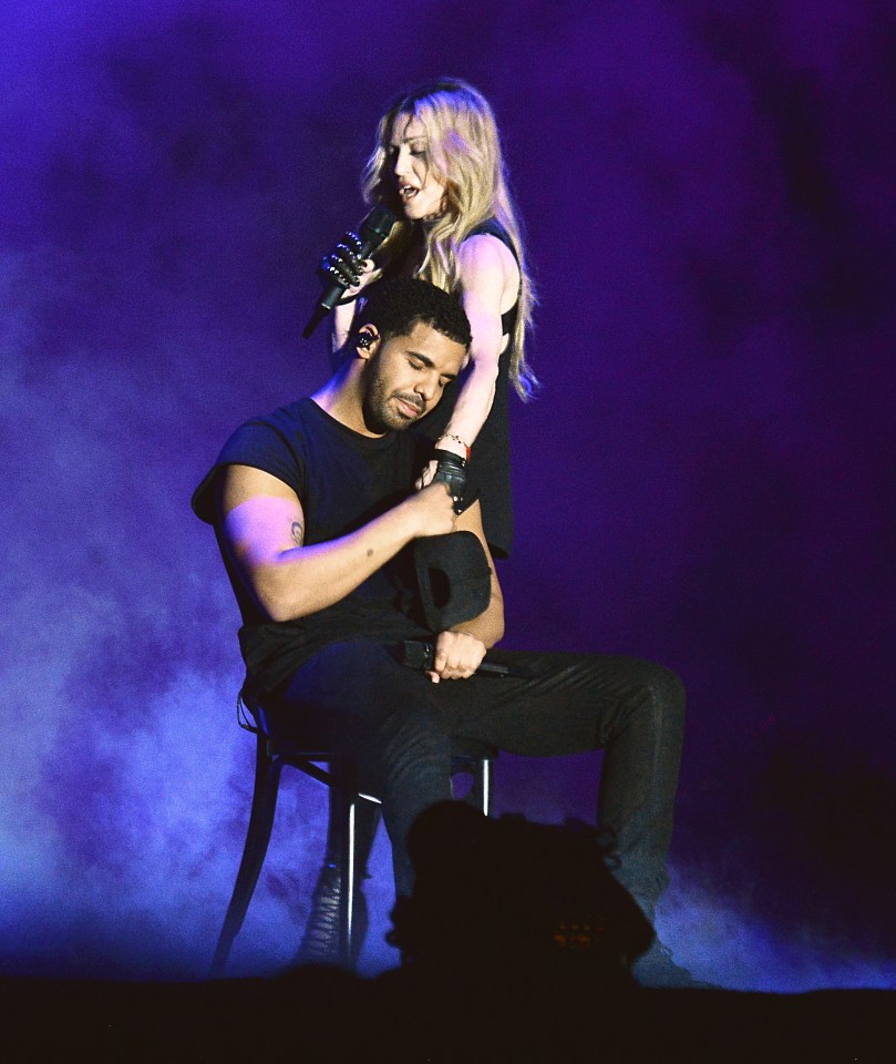 Madonna singing into a microphone with Drake seated below her, on stage at Coachella.