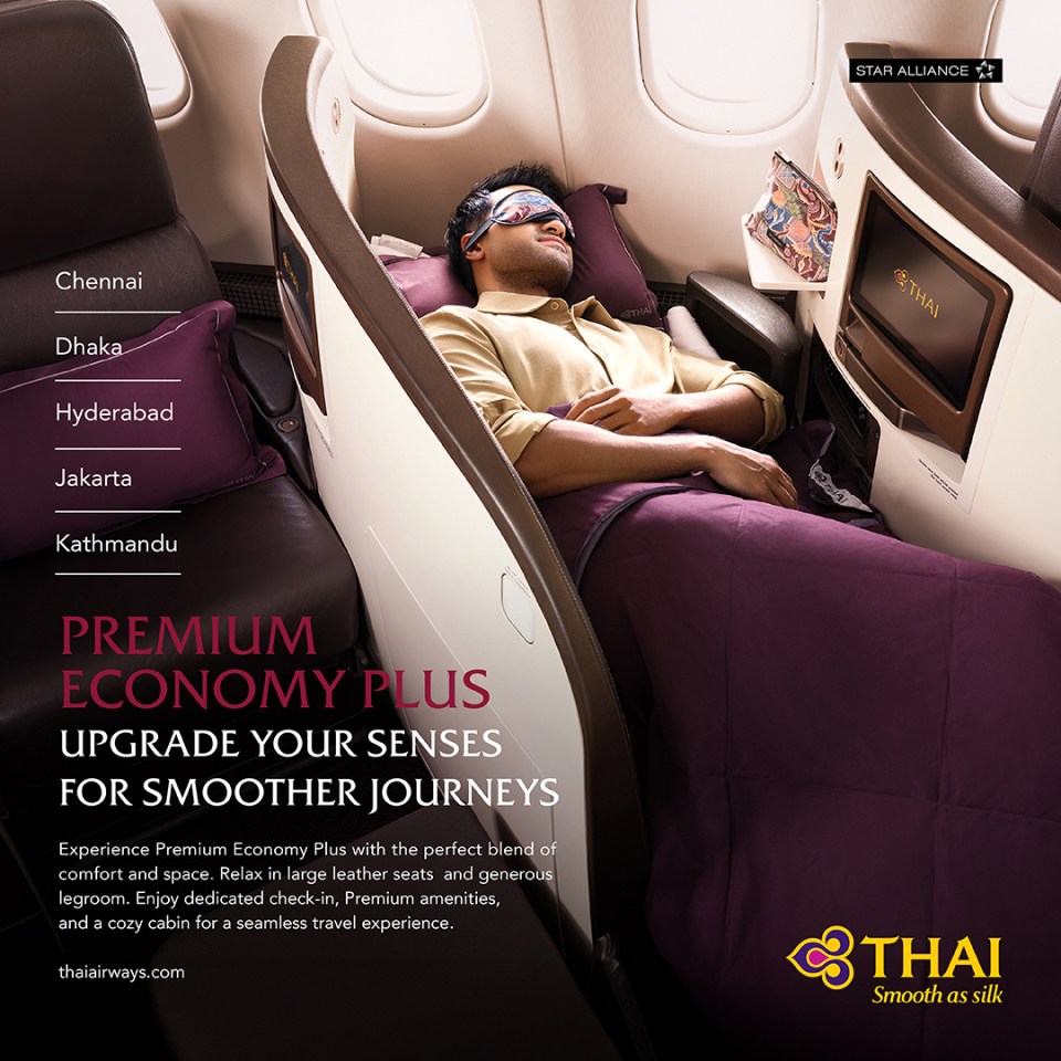 A man in a lie-flat bed in an airline's premium economy cabin.