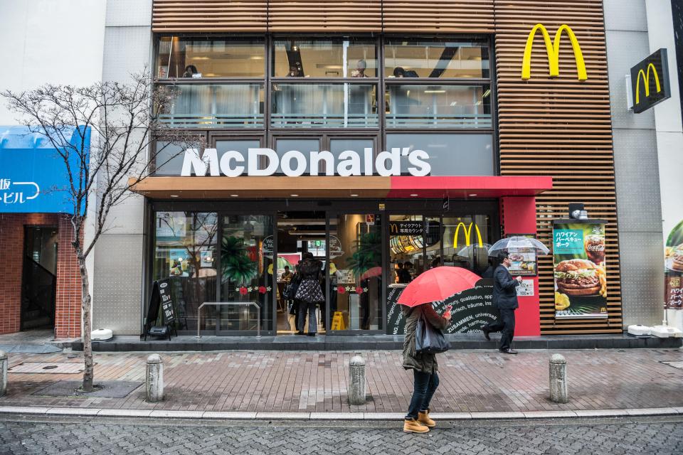 McDonald's restaurant in Tokyo, Japan, with people entering and passing by with umbrellas in the rain.
