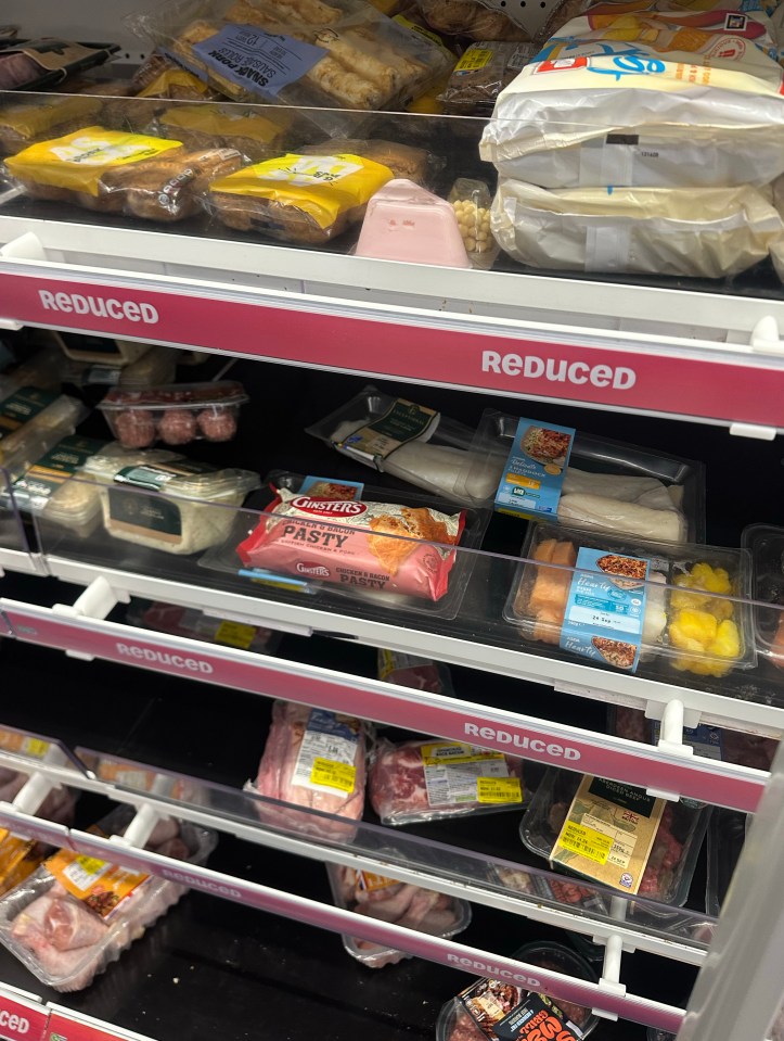 Supermarket "Reduced to clear" section with packaged food items like pastries, pasties, meat, and fish on shelves.