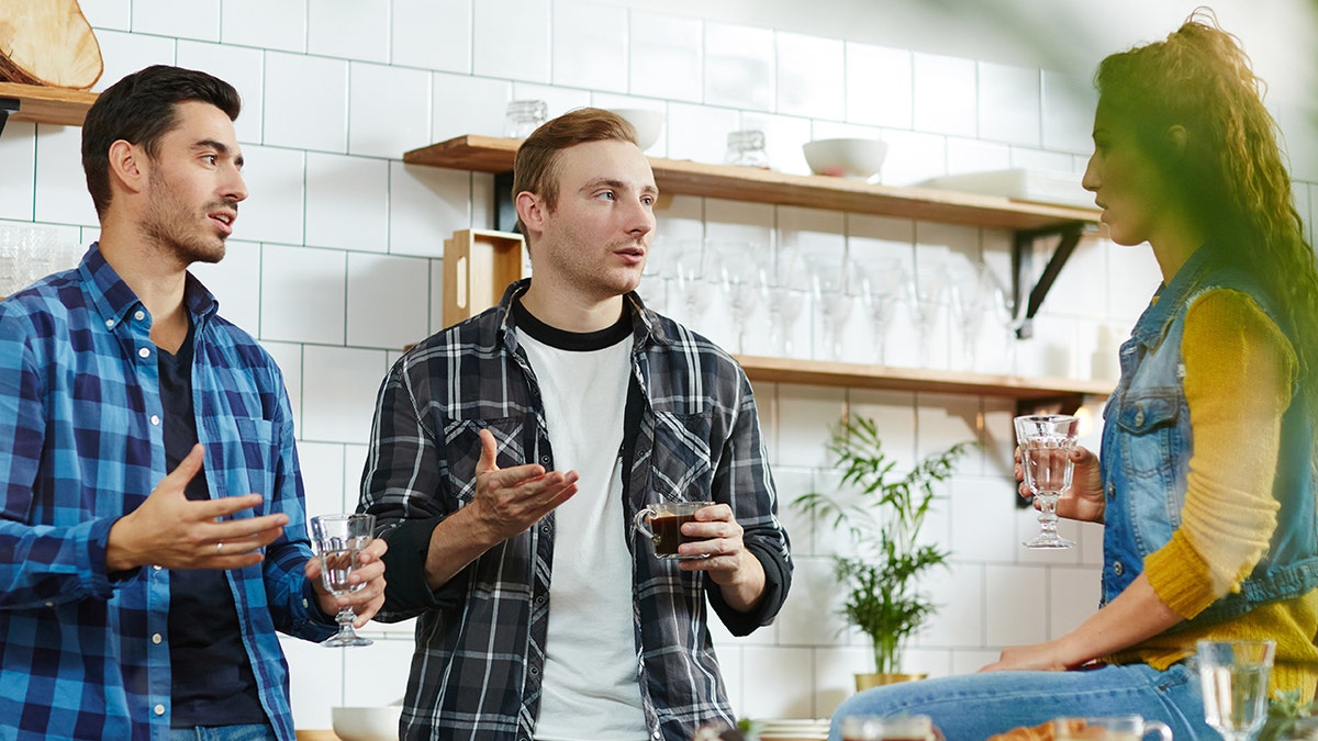 Roommates engaged in serious discussion in kitchen.