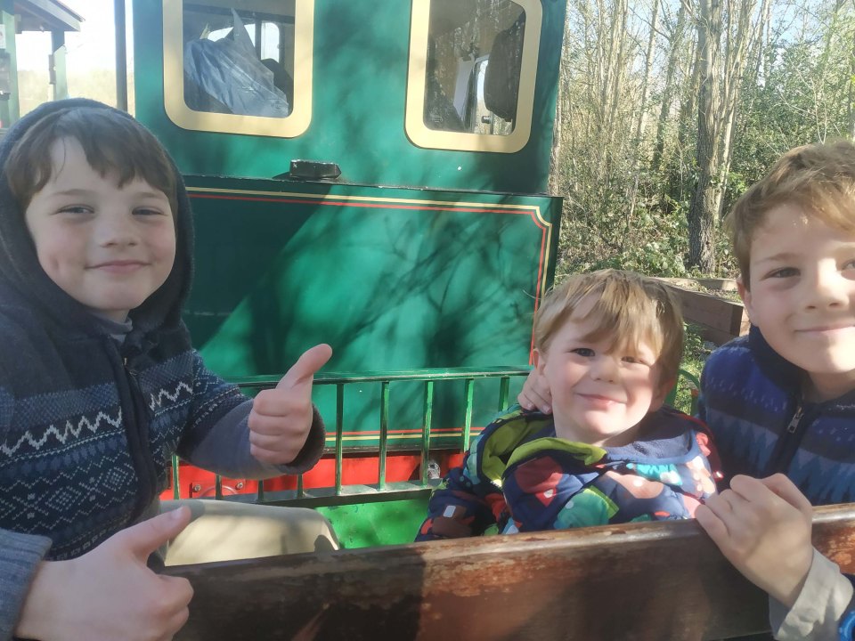 Three young boys smiling in a train car.