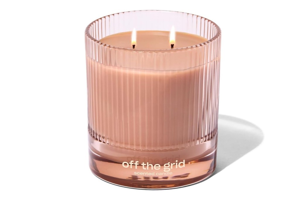 Snif "Off the Grid" scented candle in a ribbed peach-colored glass with two lit wicks.