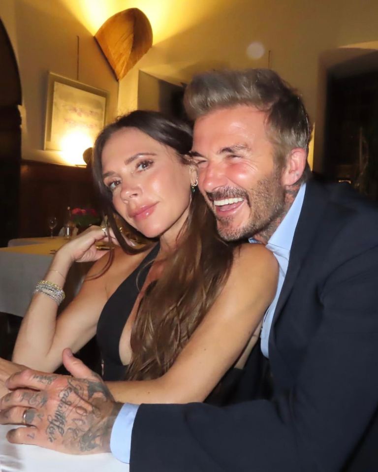 Victoria and David Beckham posing together with David laughing.