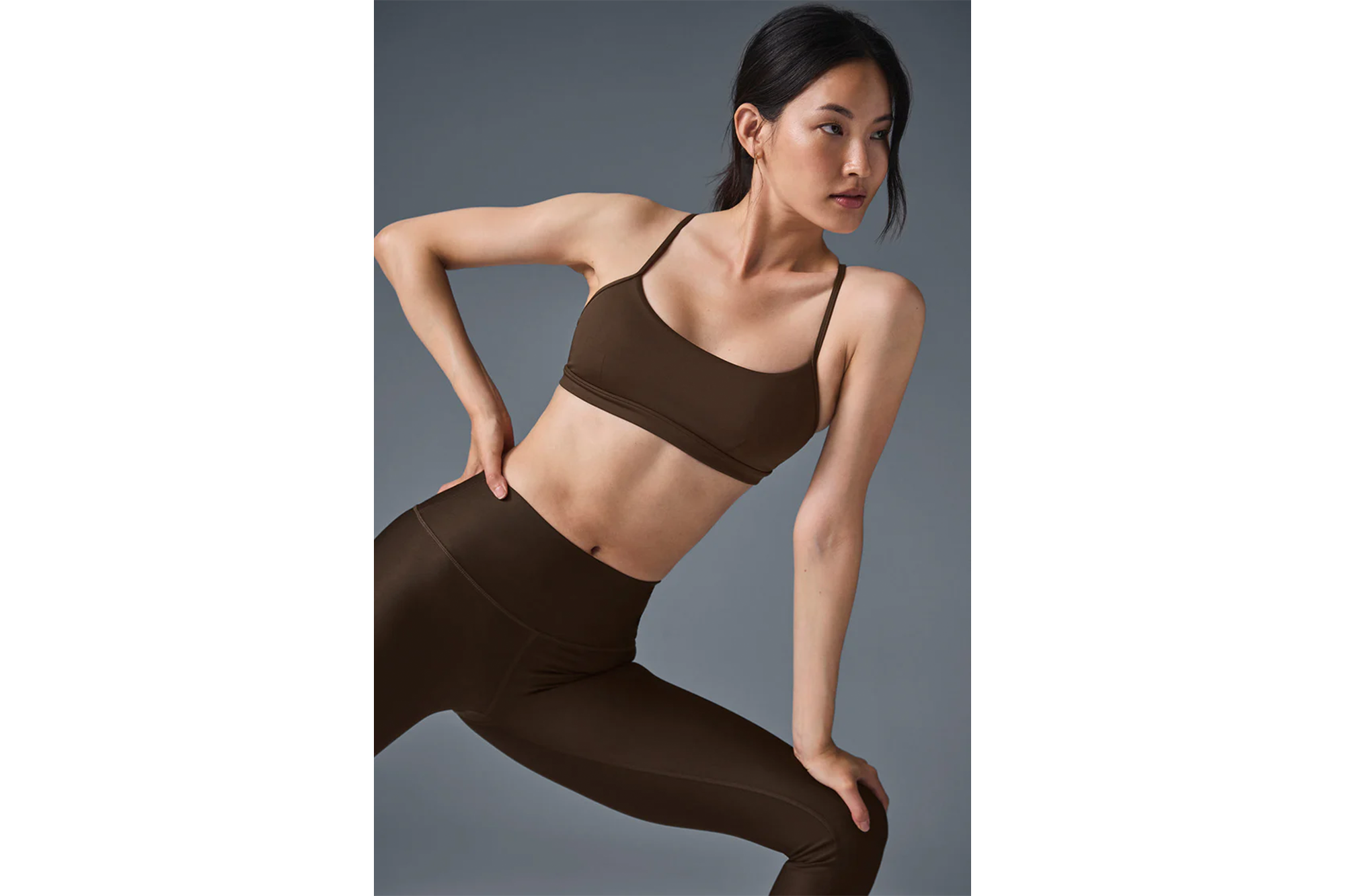 A woman models a brown bra and matching leggings.