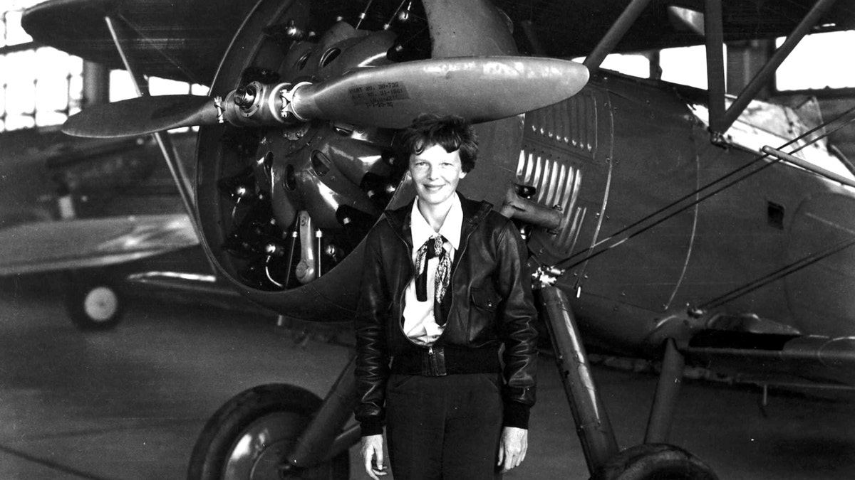 Amelia Earhart standing in front of plane