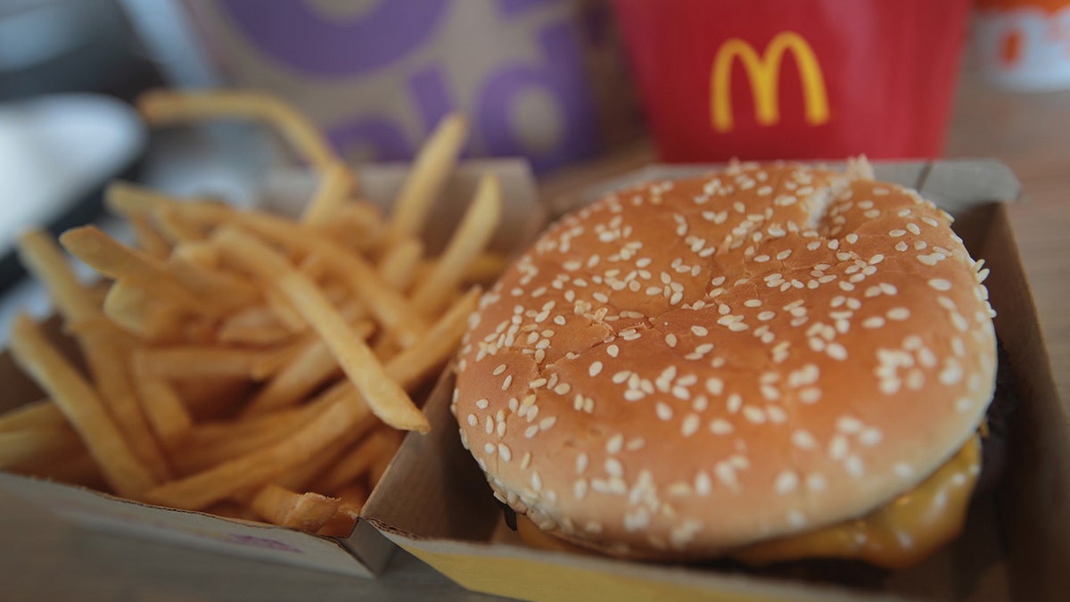 McDonald's Quarter pounder with cheese seen in box with fries and branded packaging in background